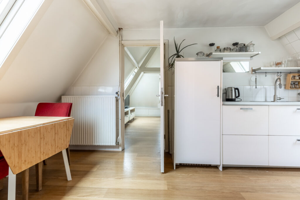 Modern attic kitchen with red chair and wooden table