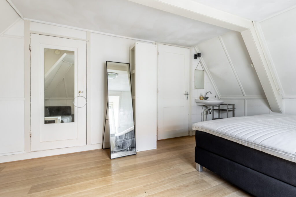 Minimalist bedroom with mirrors and a sink.