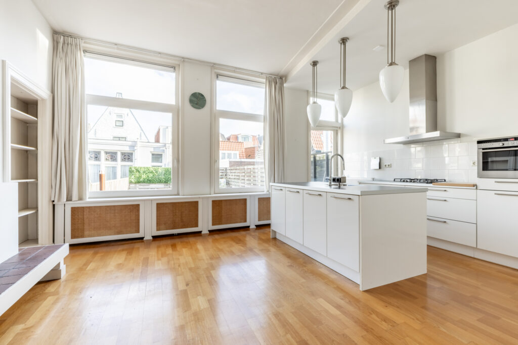 Modern kitchen with white cabinets and large windows.