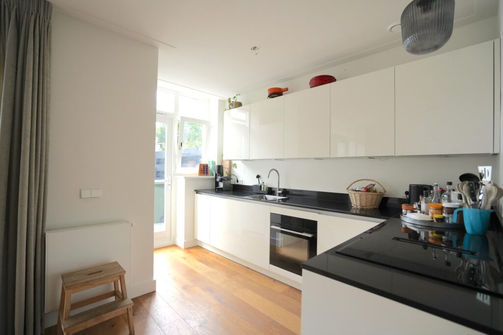 Modern kitchen with white cabinets and wood floor.