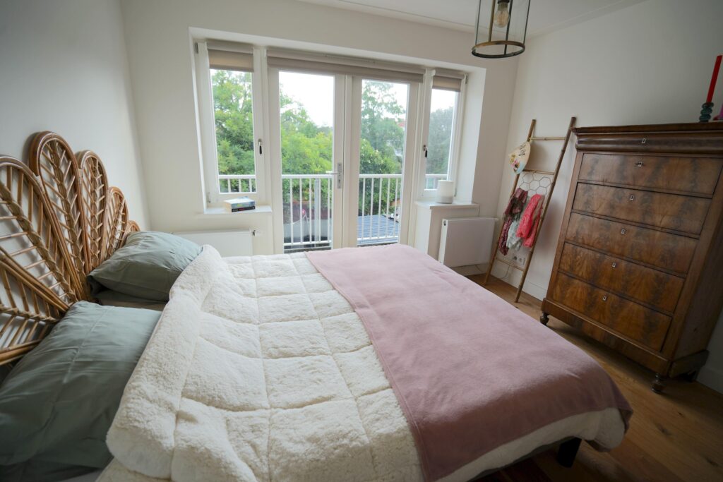 Cozy bedroom with balcony and wooden furniture.