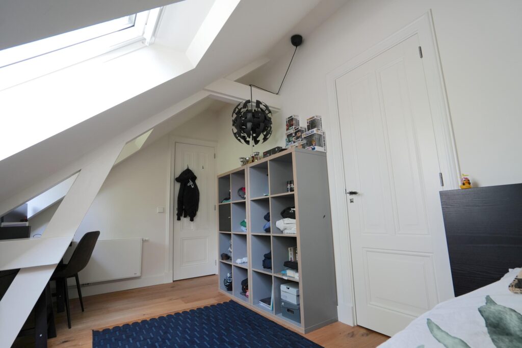 Modern attic bedroom with shelving and skylight window.