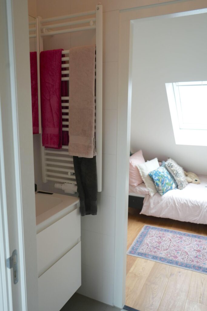 Small bathroom with towels and view into bedroom.