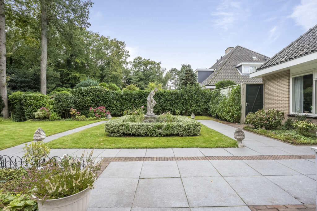 Lush garden with statue centerpiece and paved paths.