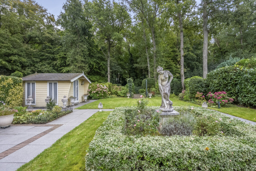 Garden with statue and small yellow house.