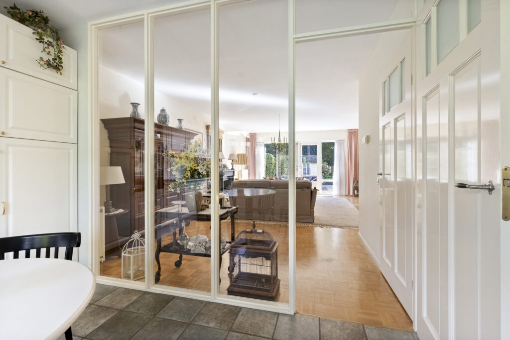 Spacious living room with glass partitions and furniture.