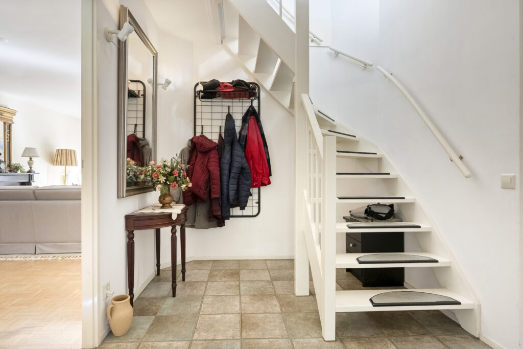 Cozy foyer with staircase and coats hanging.