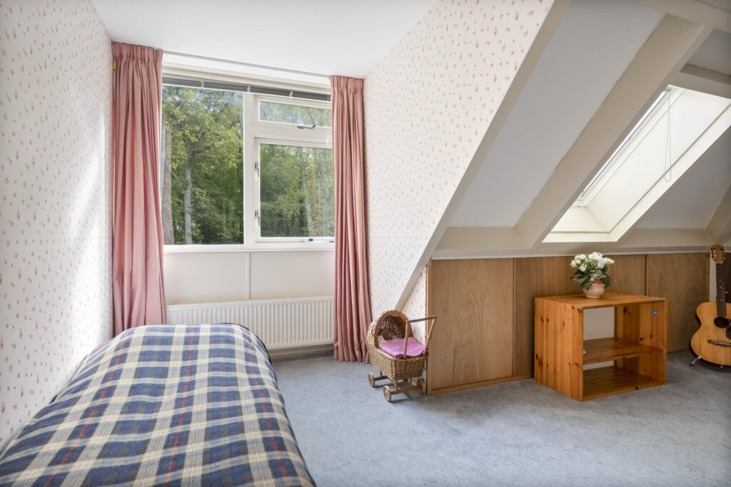 Cozy attic bedroom with plaid blanket and guitar.
