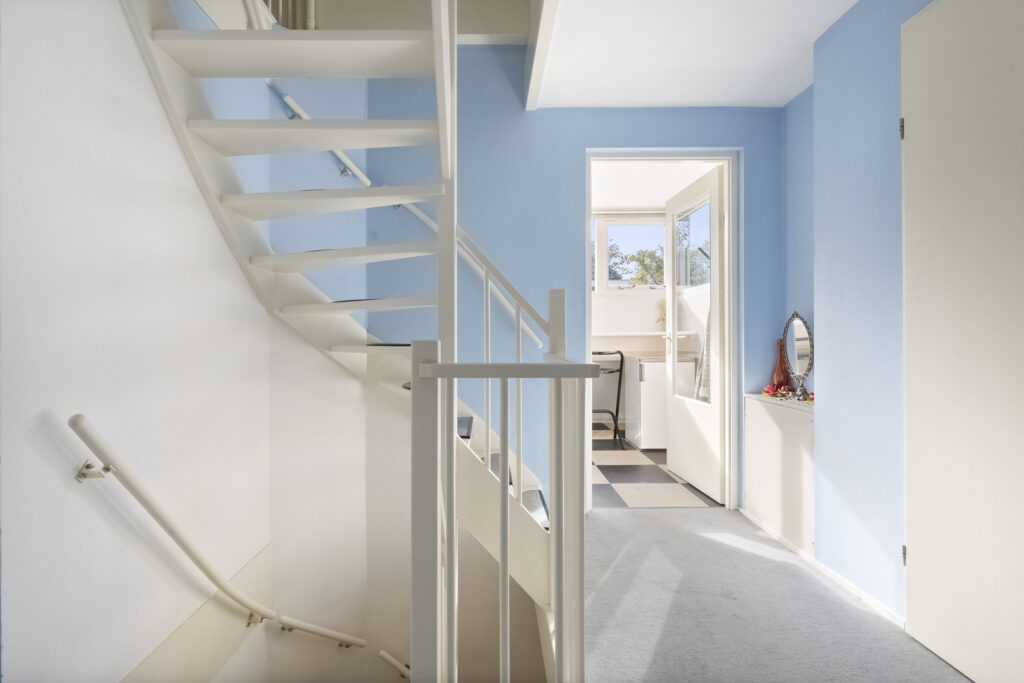Bright stairway with blue walls and open door.