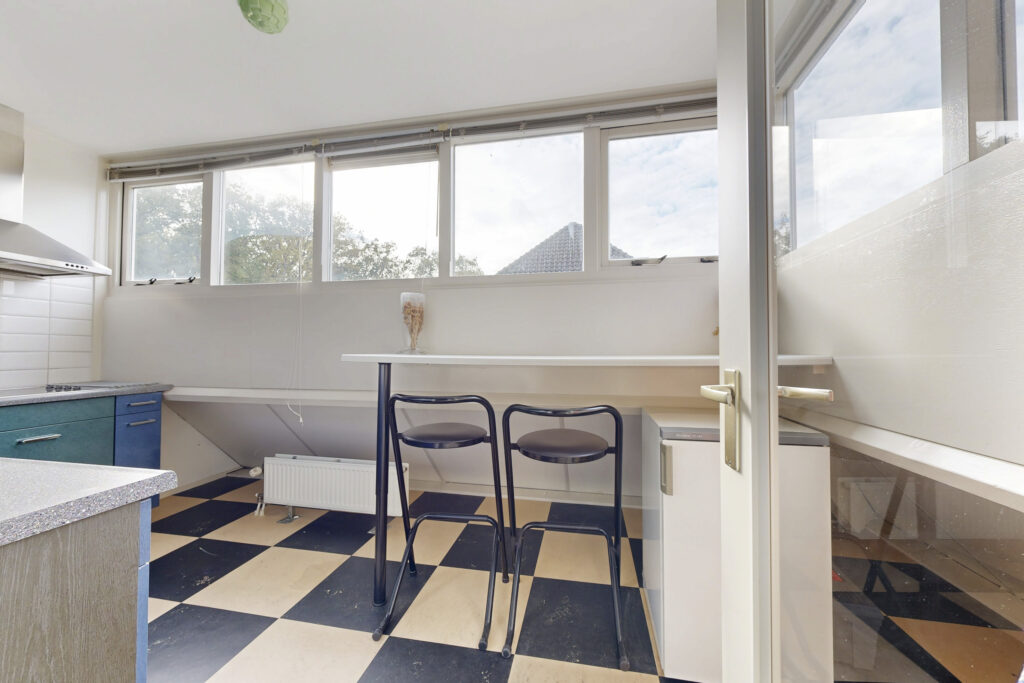 Modern kitchen with checkered floor and bar stools.