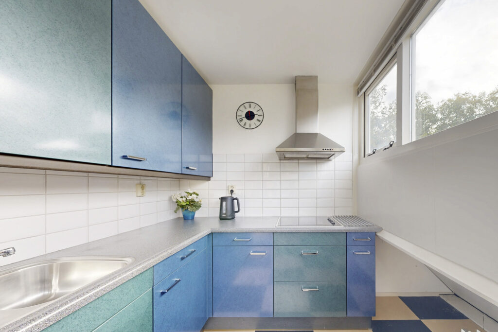 Modern kitchen with blue cabinets and stainless steel hood.