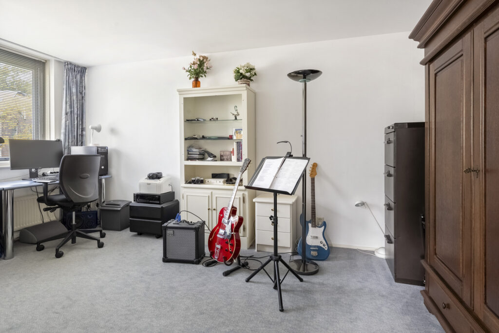 Home office with guitars and music stand.