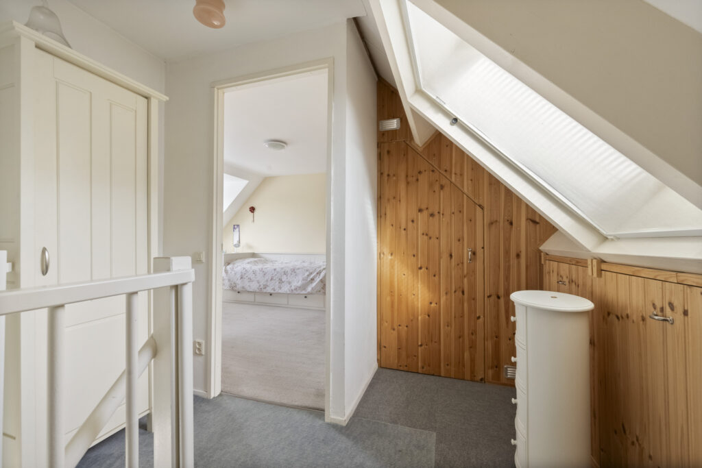 Attic bedroom with wooden wall and skylight window.