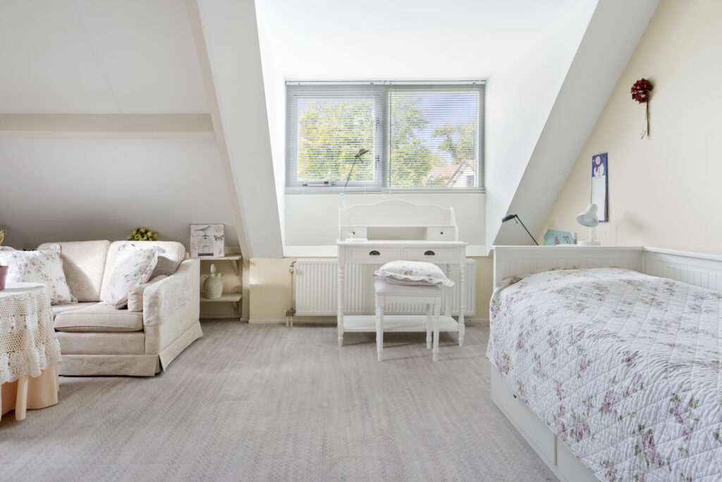 Bright attic bedroom with cozy sofa and floral bedding.