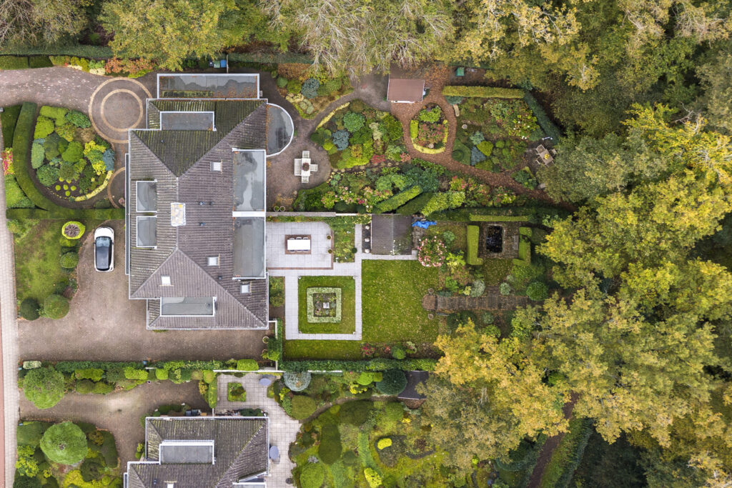 Aerial view of house with gardens and pathways.