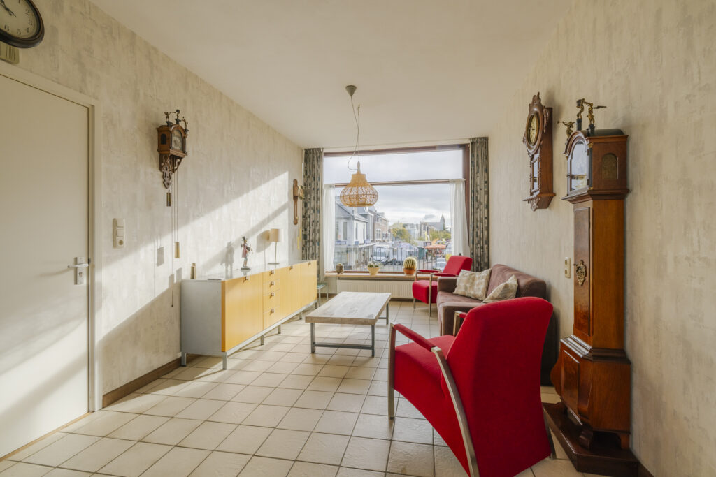 Cozy living room with red chairs and vintage clocks.