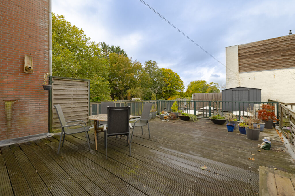Spacious wooden deck with chairs and garden view.