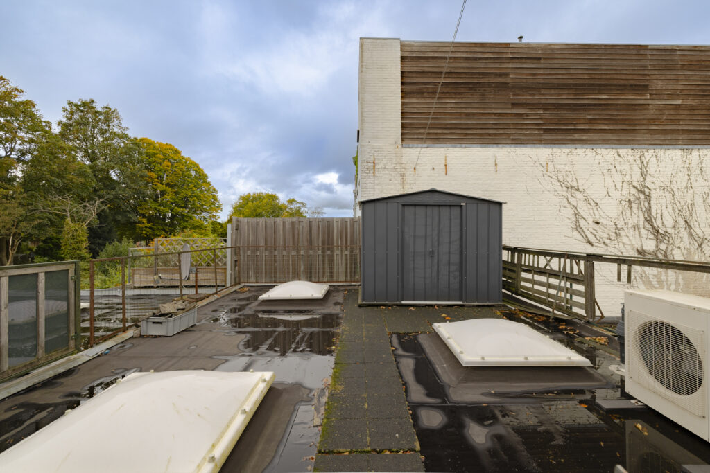 Rooftop with storage shed and skylights, overcast sky.