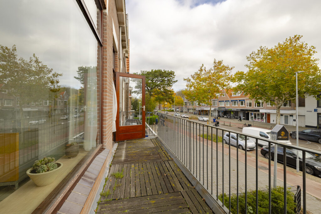 Balcony overlooking street with trees and shops.