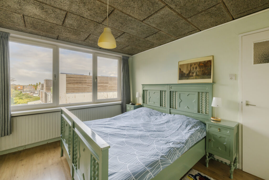 Cozy bedroom with green vintage furniture and large window.