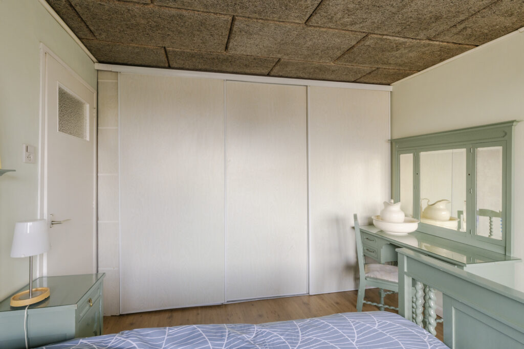 Bedroom with green furniture and white closet.