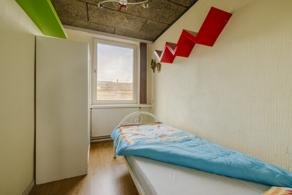 Small bedroom with single bed and shelves