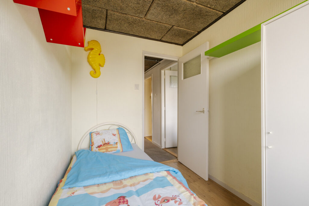 Small bedroom with single bed and seahorse decor.