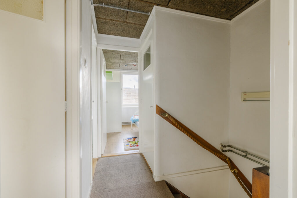 Carpeted hallway with staircase and natural light.