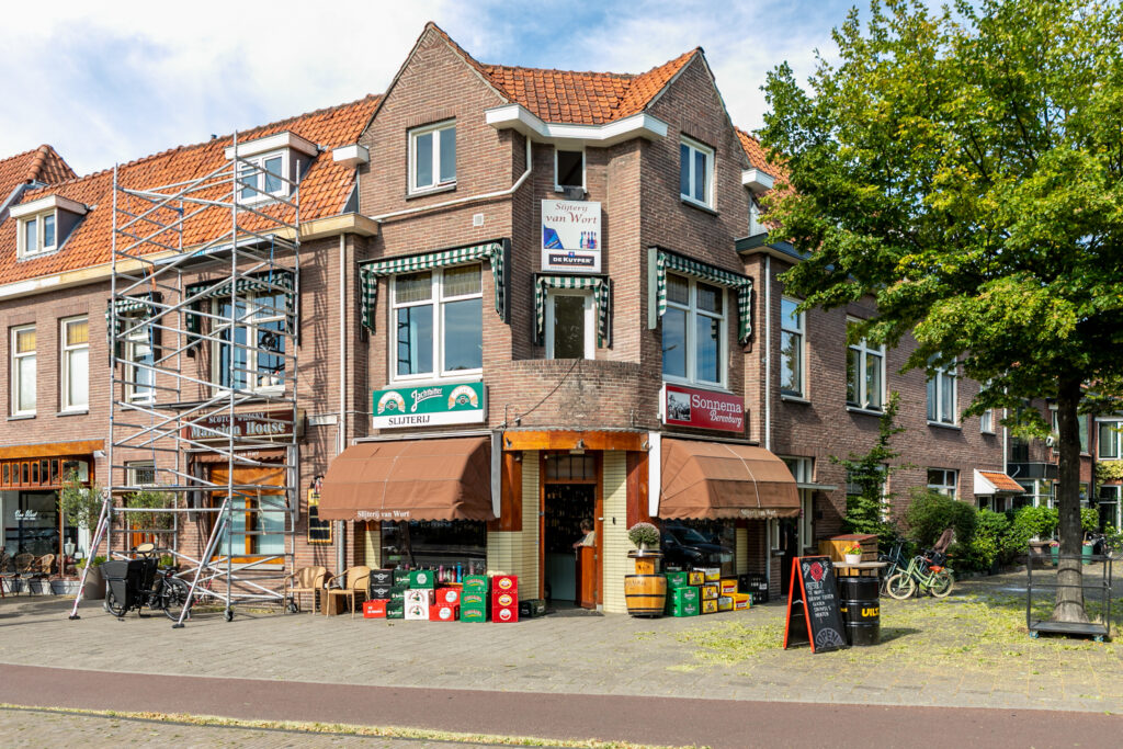 Corner liquor store with brown awnings, bicycles nearby.