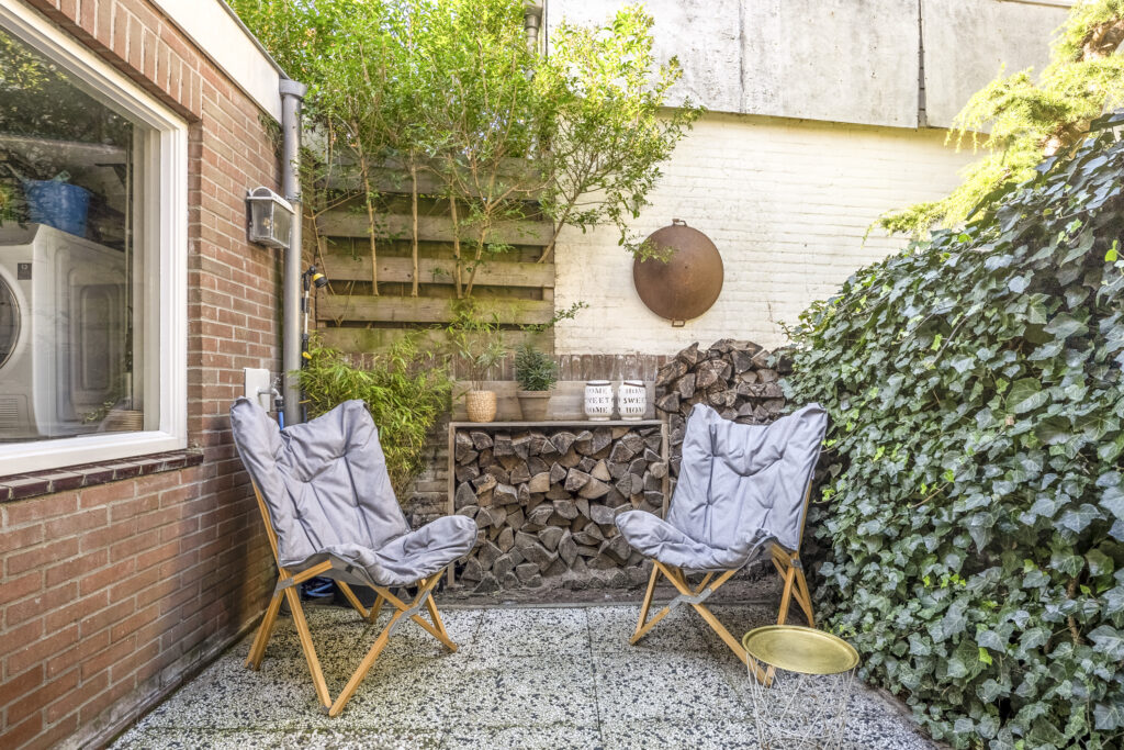 Cozy patio with chairs and greenery.