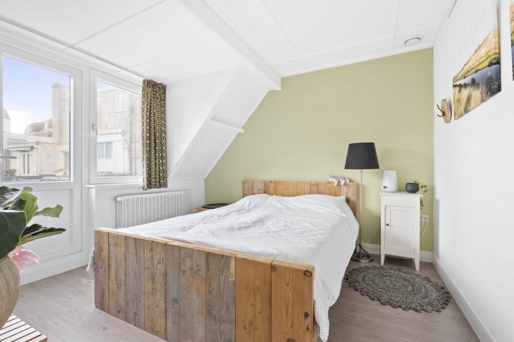 Cozy bedroom with wooden bed and green wall.