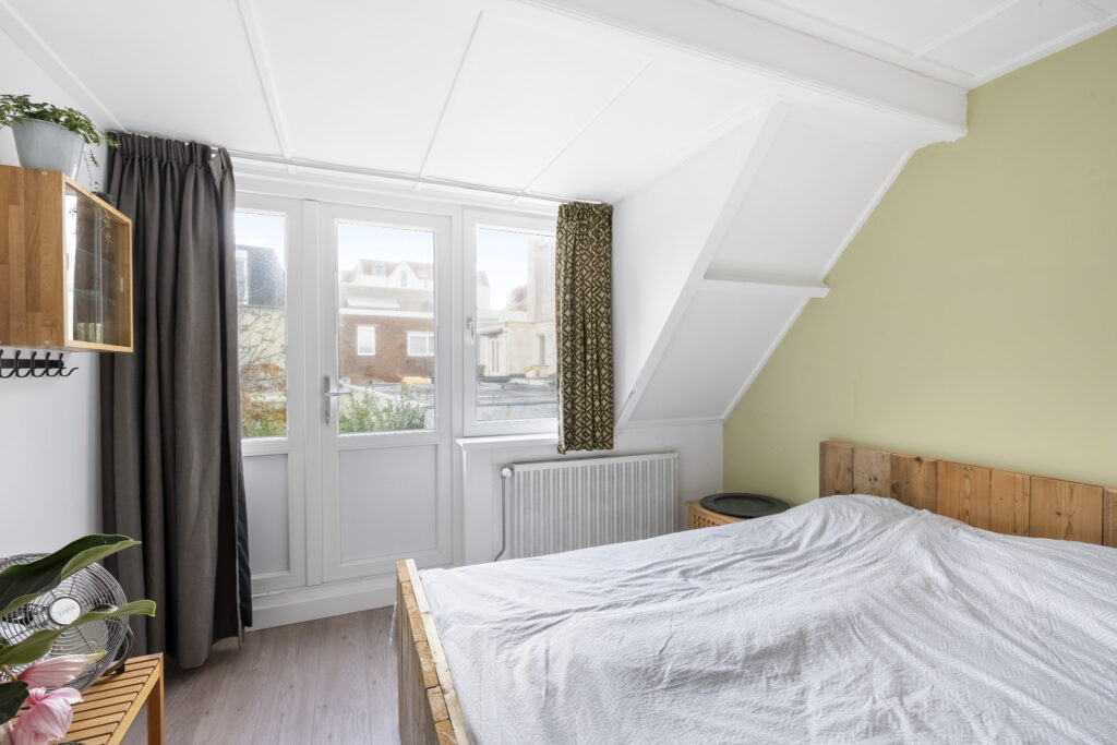 Bright bedroom with large windows and wooden bed