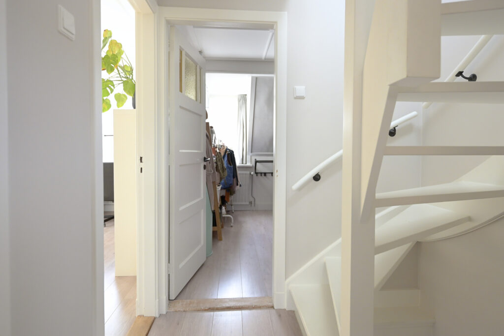 Bright hallway with open door and staircase view.