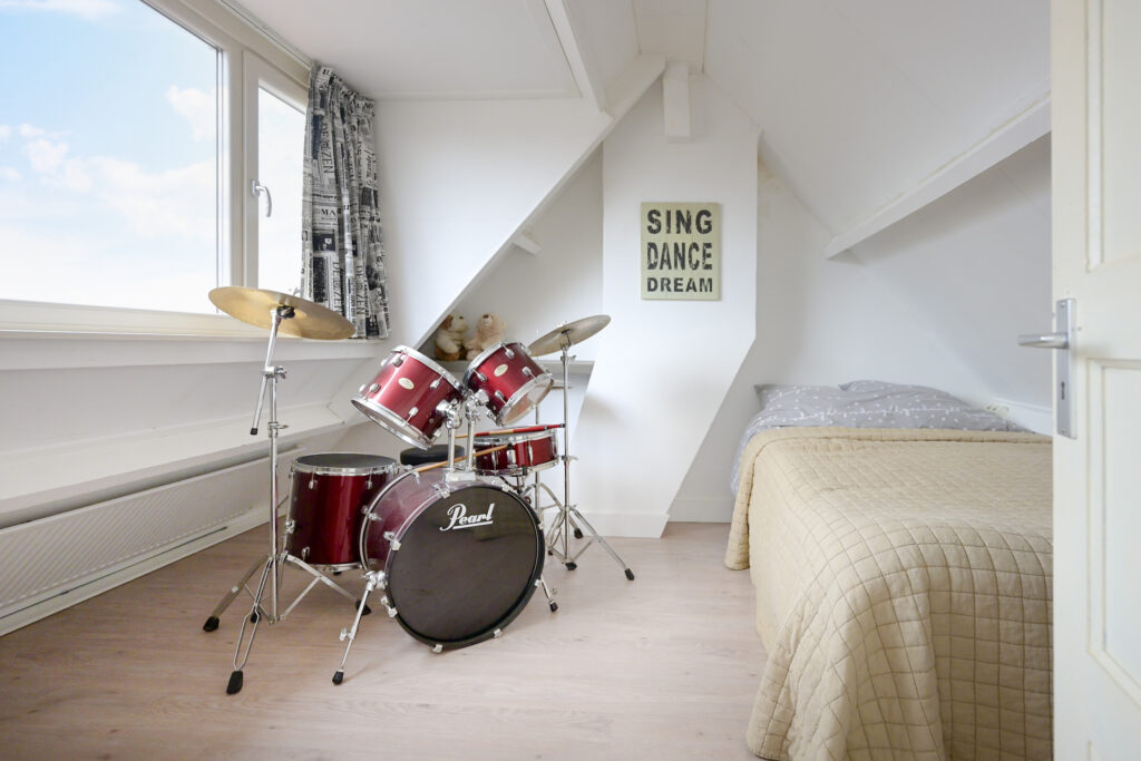 Bedroom with drum set and motivational poster.