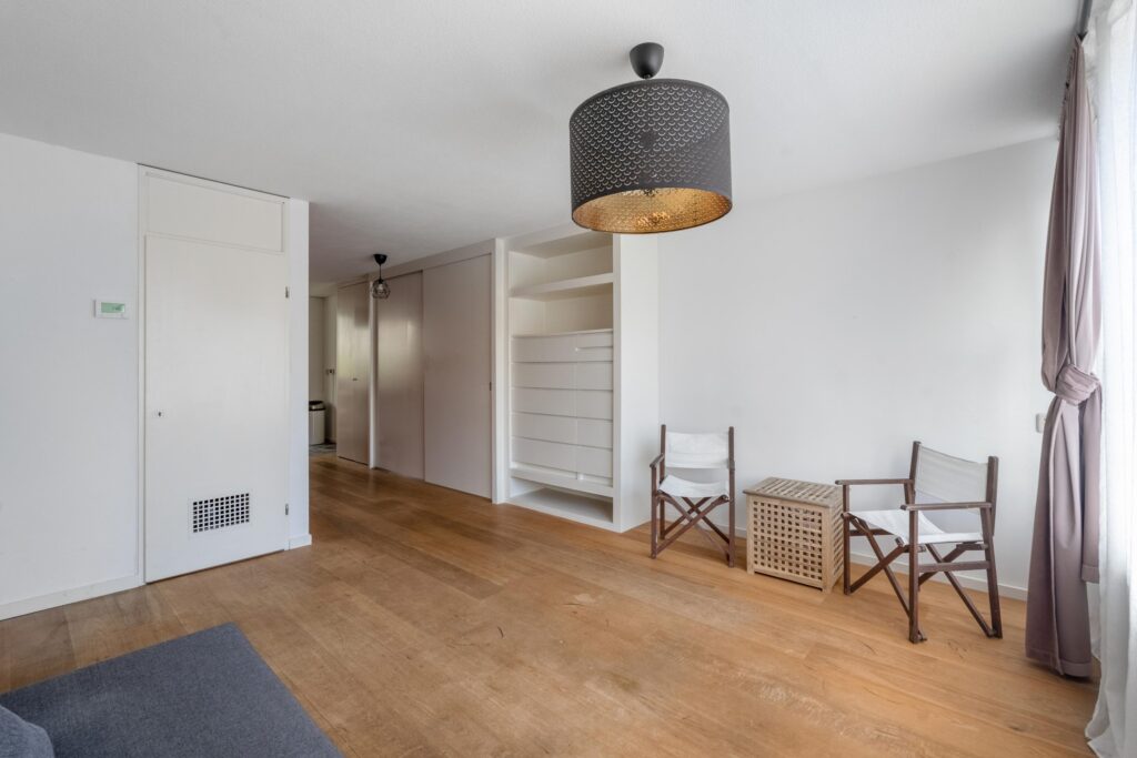 Minimalist living room with wooden floor and chairs.