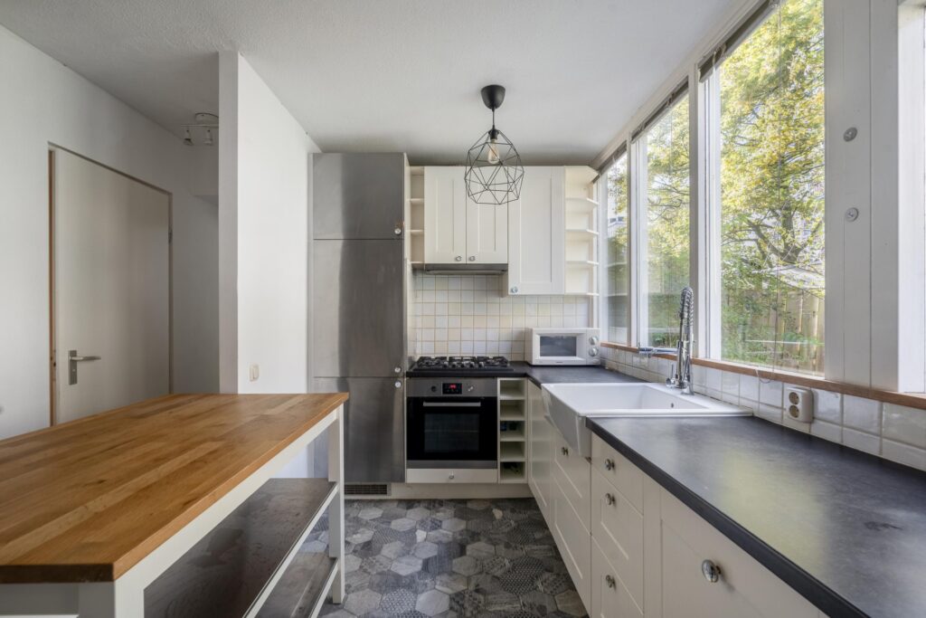 Modern kitchen with wooden island and large windows.