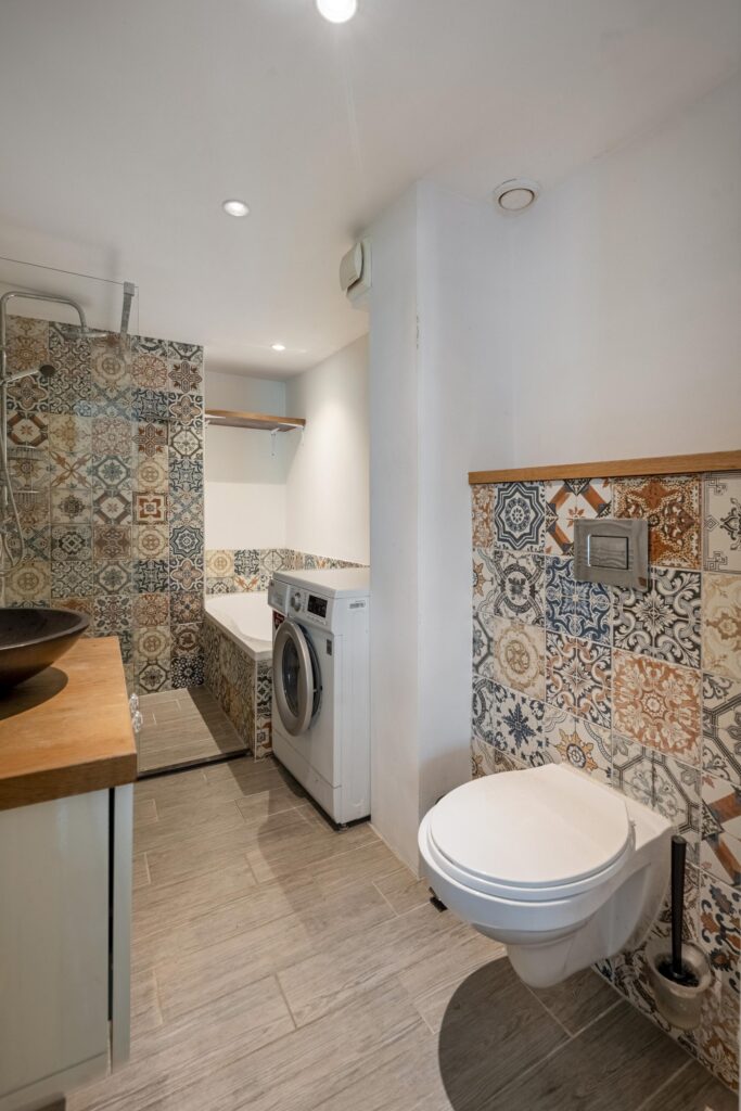 Bathroom with washer and colorful patterned tiles.