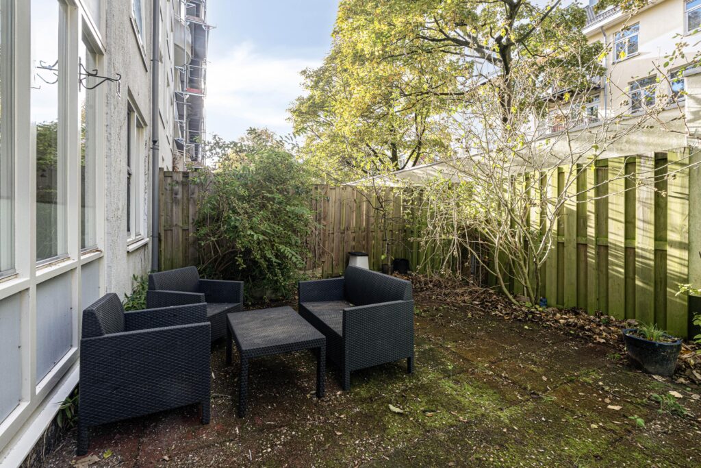 Outdoor patio with black wicker furniture, fenced backyard.