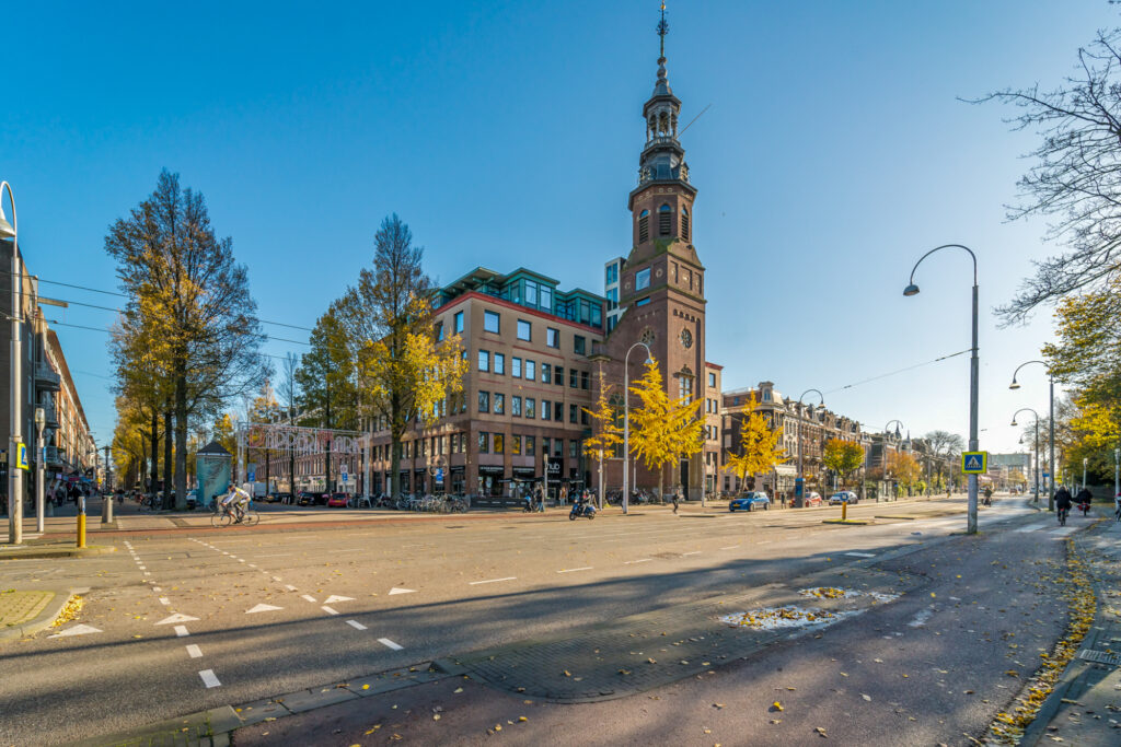 City street with clock tower and autumn trees.