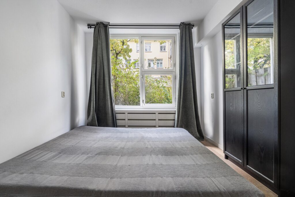 Cozy bedroom with window and dark curtains.
