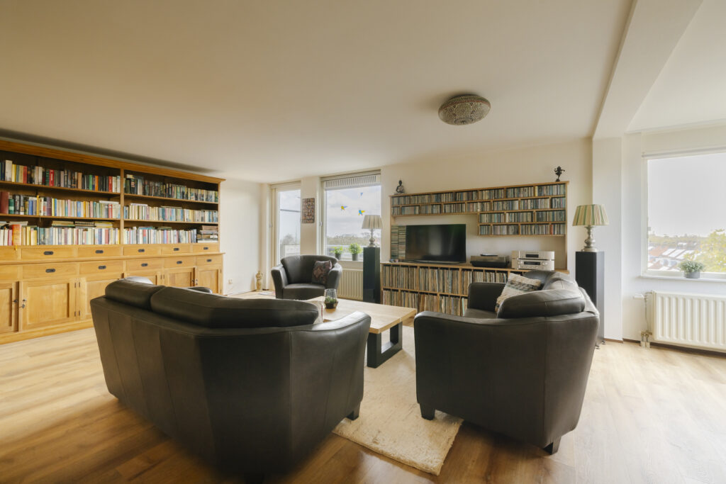 Spacious living room with bookshelves and leather sofas.