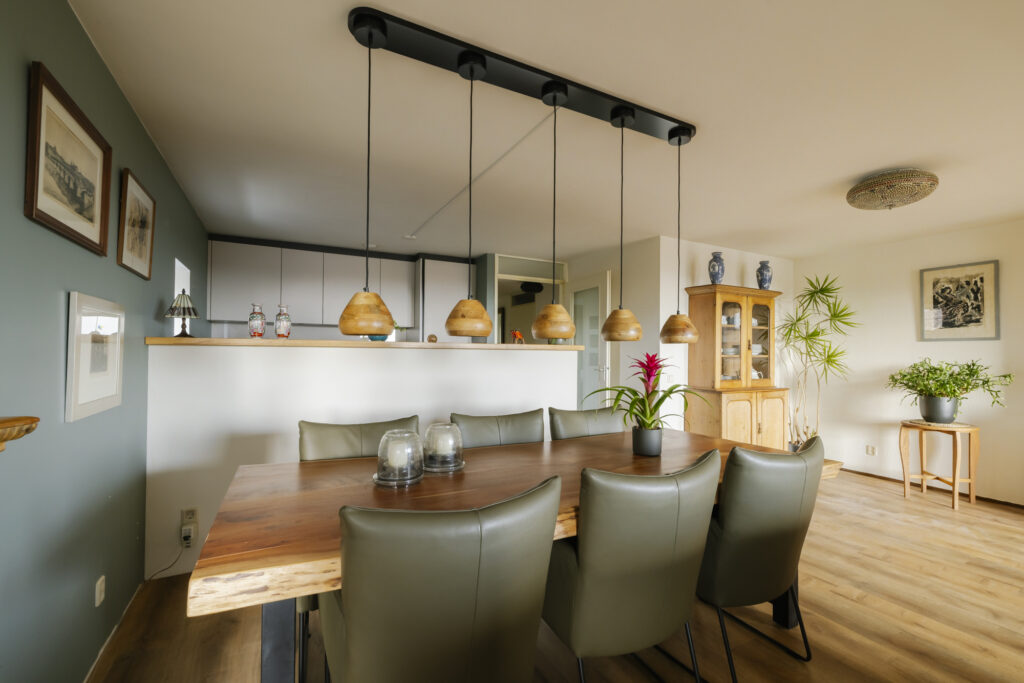 Dining room with wooden table and hanging lights.