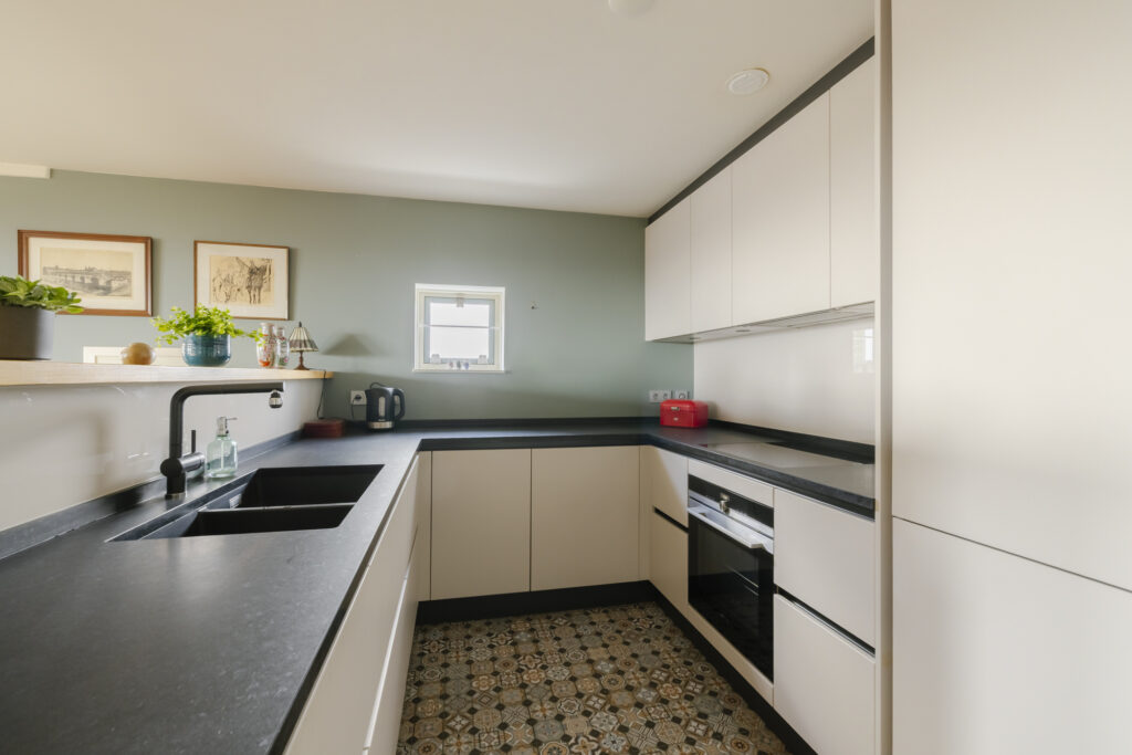 Modern kitchen with black countertops and green walls.