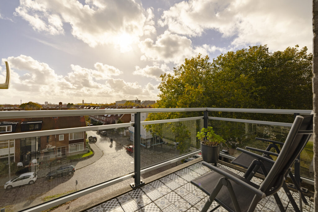 Sunny balcony view with two chairs and plants.