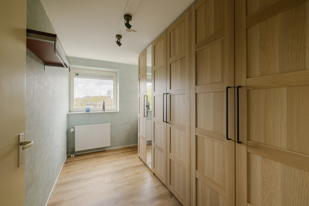 Empty hallway with wooden wardrobes and window view.