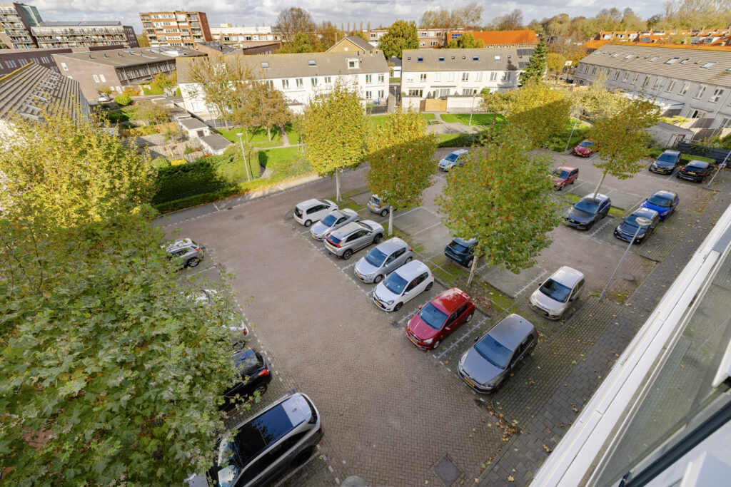 Aerial view of parking lot with cars and trees.
