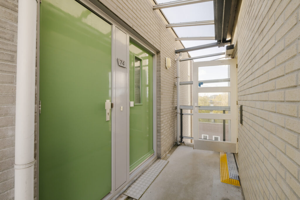 Green apartment entrance with glass panels and number 74