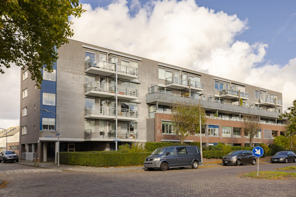 Modern apartment building with balconies and parked cars.