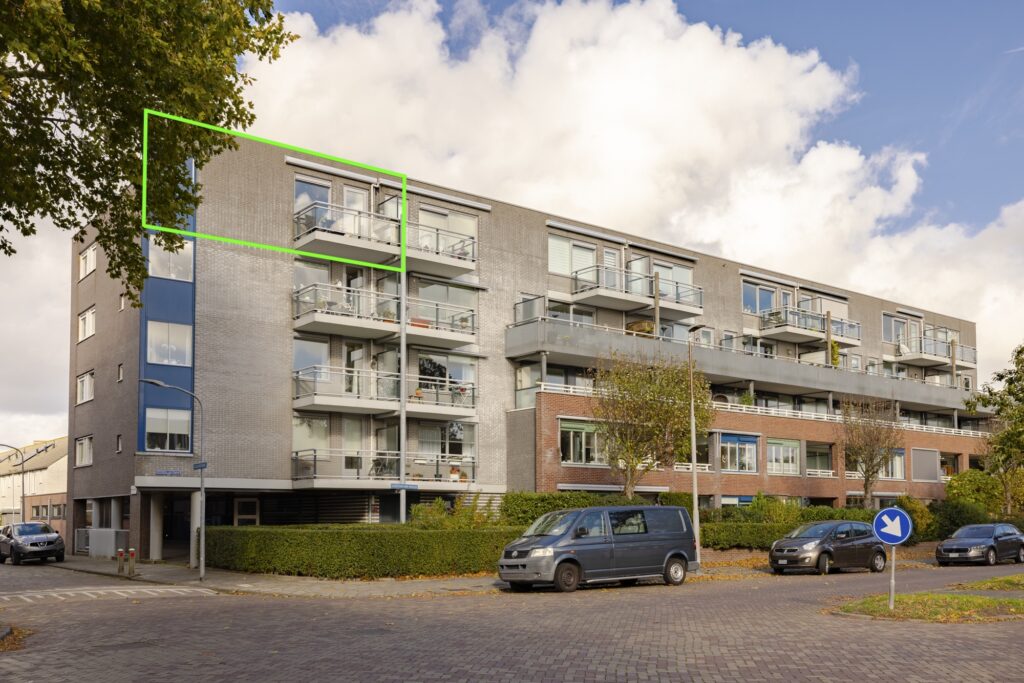 Modern apartment building with balconies and parked cars.