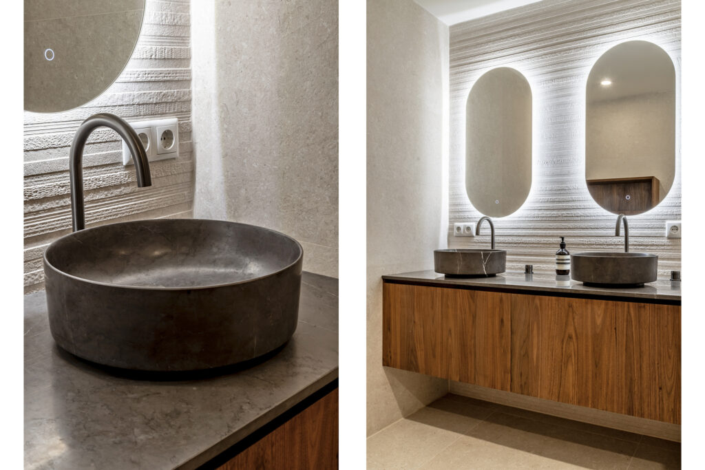 Modern bathroom with circular stone sinks and mirrors.